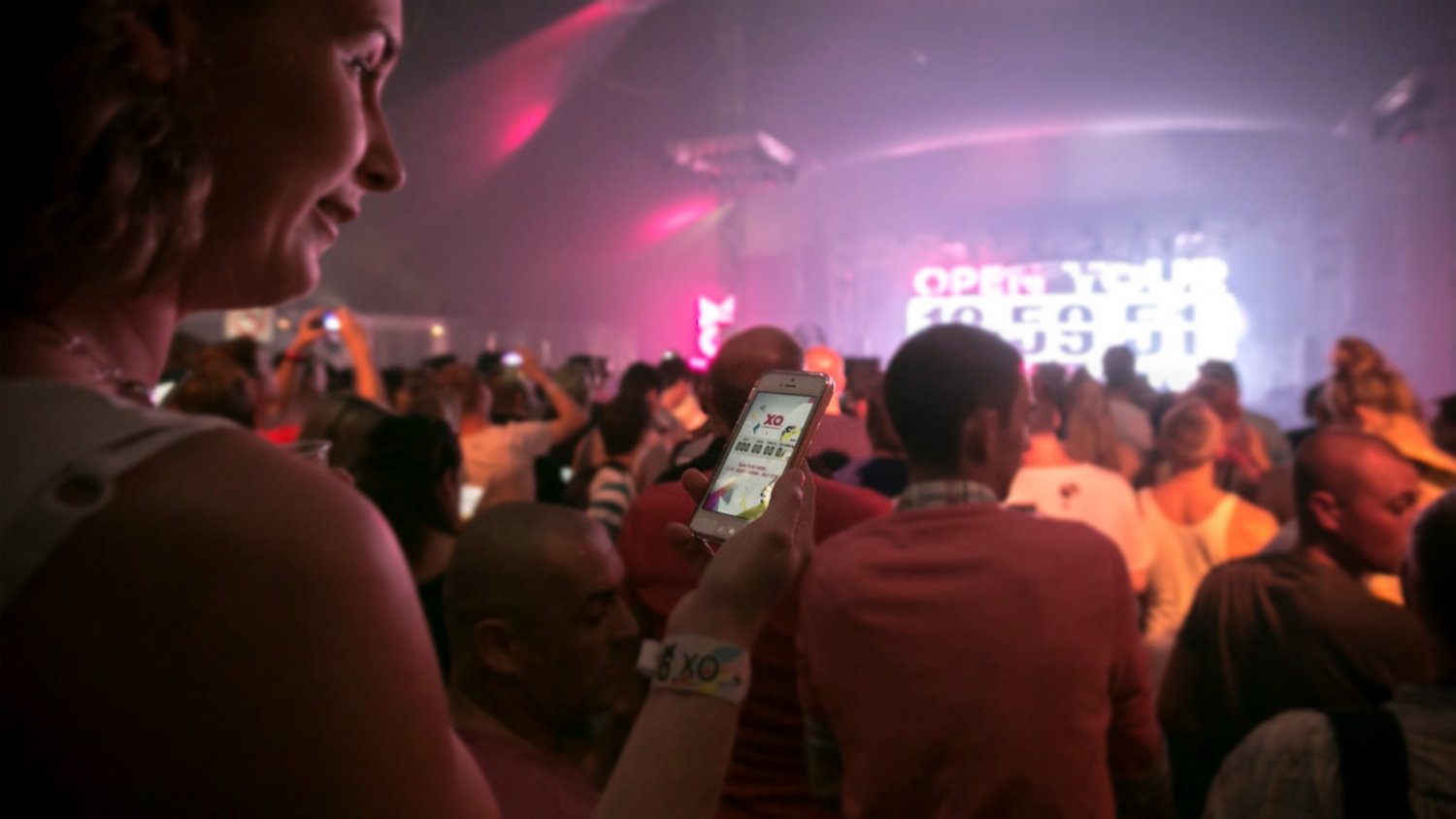 Festival crowd with phones lighting up in sync with the show