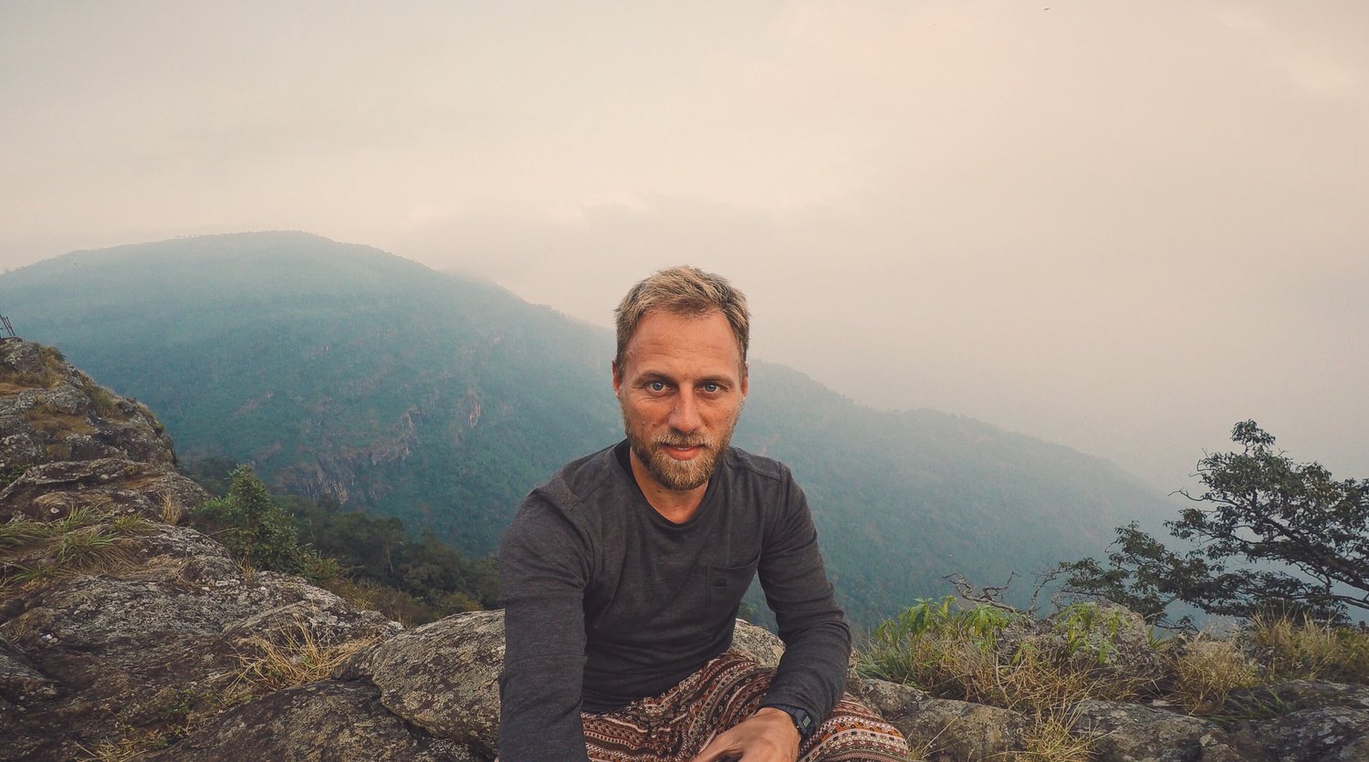 Tim Koppers sitting on a rock in the mountains